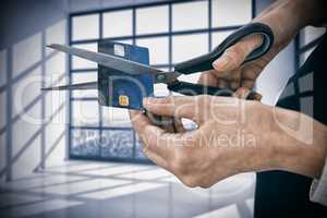 Composite image of businesswoman cutting credit card with scissors