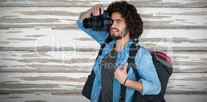 Composite image of male photographer carrying tripod case while photographing