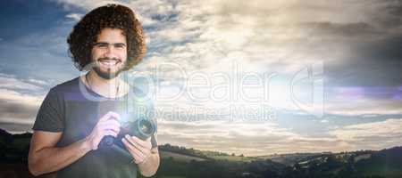 Composite image of portrait of smiling male photographer holding camera
