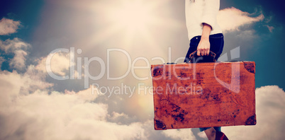 Composite image of low section of woman carrying vintage suitcase