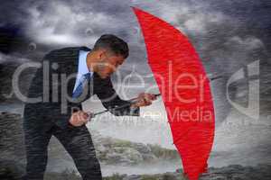 Composite image of businessman defending with red umbrella