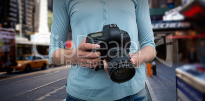 Composite image of mid section of female photographer holding digital camera