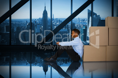 Composite image of businessman leaning on cardboard boxes against white background