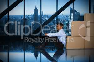 Composite image of businessman leaning on cardboard boxes against white background