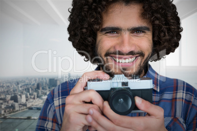 Composite image of close up portrait of smiling photographer holding camera