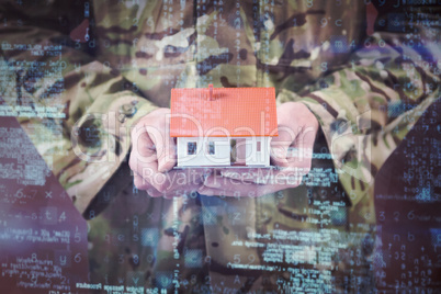 Composite image of mid section of soldier holding model home