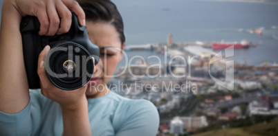 Composite image of young female photographer photographing through digital camera