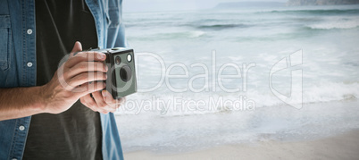 Composite image of mid section of photographer holding vintage camera