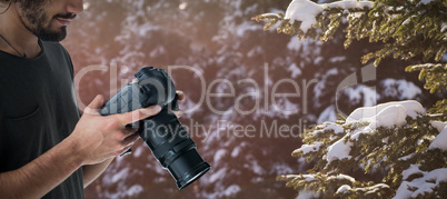 Composite image of young male photographer holding digital camera
