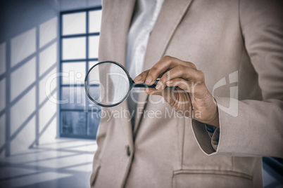 Composite image of mid section of businesswoman holding magnifying glass