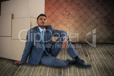 Composite image of businessman leaning on cardboard boxes against white background