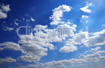 Blue sky with white clouds in the rays of the bright sun