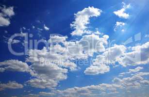 Blue sky with white clouds in the rays of the bright sun