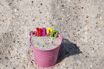 Word blog of wooden letters in a pink bucket with sand
