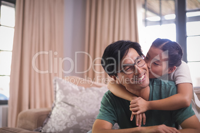 Daughter kissing father on cheeks in living room