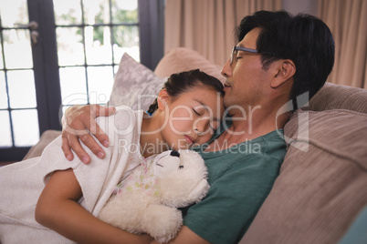 Father and daughter relaxing on sofa in living room