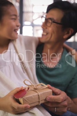 Daughter giving gift box to father in living room