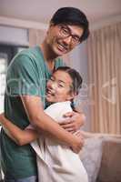 Smiling father and daughter hugging each other in living room