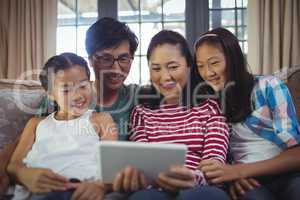 Smiling family using digital tablet together in living room