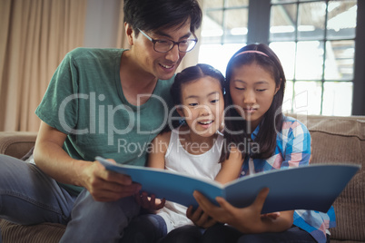 Father and siblings watching photo album together in living room