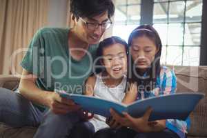 Father and siblings watching photo album together in living room