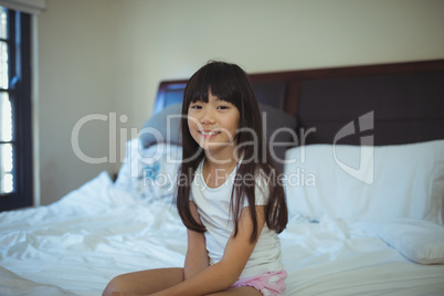 Smiling girl sitting on bed in the bed room