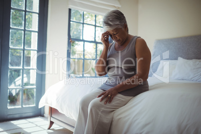 Upset senior woman touching head at home