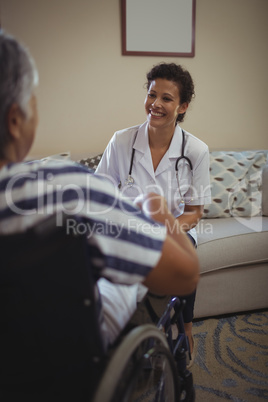 Female doctor interacting with senior woman on wheelchair