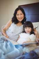 Mother and daughter holding book on bed in bed room