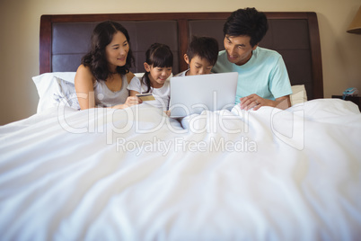 Family using laptop together in bedroom