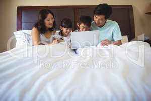 Family using laptop together in bedroom