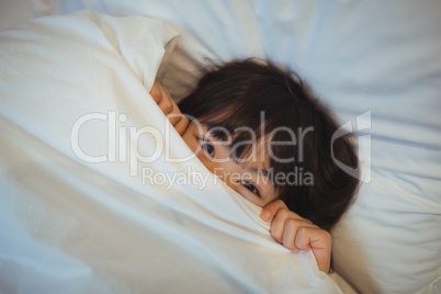 Boy hiding in bed under the blanket