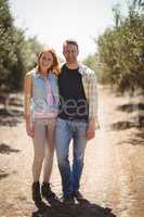 Portrait of smiling young couple standing at olive farm on sunny day
