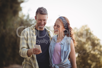 Cheerful young man showing mobile to woman