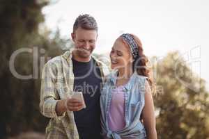 Cheerful young man showing mobile to woman