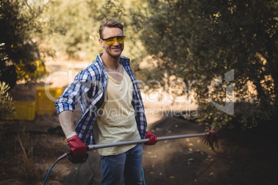 Smiling man holding rake at olive farm