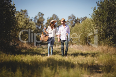 Young couple holding hands while carrying picnic basket