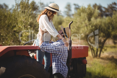 Young couple looking at each other while standing by tractor