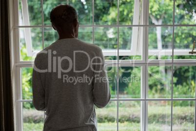 Rear view of senior man standing against windows