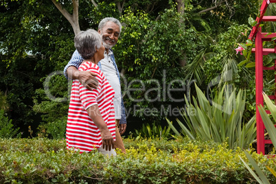 Smiling senior couple walking together amidst plants