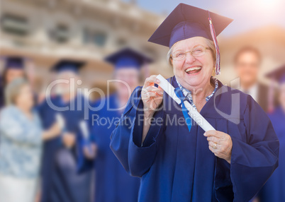 Happy Senior Adult Woman In Cap and Gown At Outdoor Graduation C