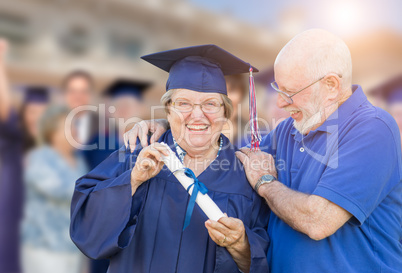 Senior Adult Woman In Cap and Gown Being Congratulated By Husban