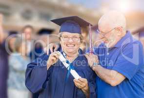 Senior Adult Woman In Cap and Gown Being Congratulated By Husban