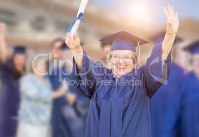 Happy Senior Adult Woman In Cap and Gown At Outdoor Graduation C