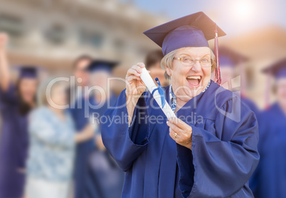 Happy Senior Adult Woman In Cap and Gown At Outdoor Graduation C