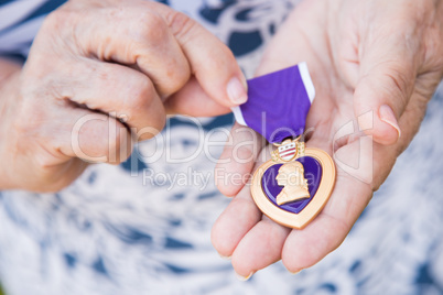 Senior Woman Holding The Military Purple Heart Medal In Her Hand