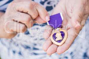 Senior Woman Holding The Military Purple Heart Medal In Her Hand