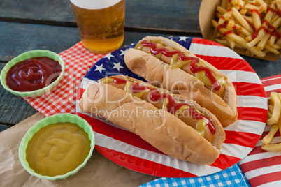 Hot dog served on plate with french fries and sauce