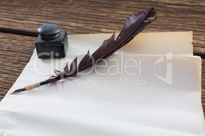 Quill feather, ink bottle and blank document on wooden table