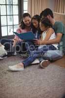 Family watching photo album together in living room